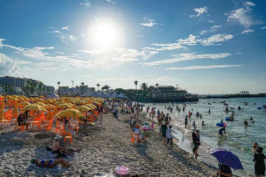 Visitors enjoying the shoreline at Hamdeok Beach
